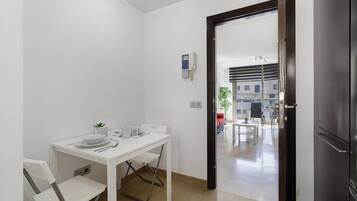 Cocina compacta con una mesa blanca para dos personas, una planta pequeña y un refrigerador moderno.