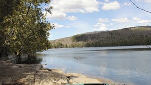 En stilla sjö med en grön kajak vid en stenig strand.