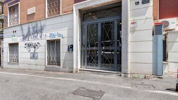 Un edificio con un gran portón de garaje, grafitis en la pared y una tapa de alcantarilla en el suelo.