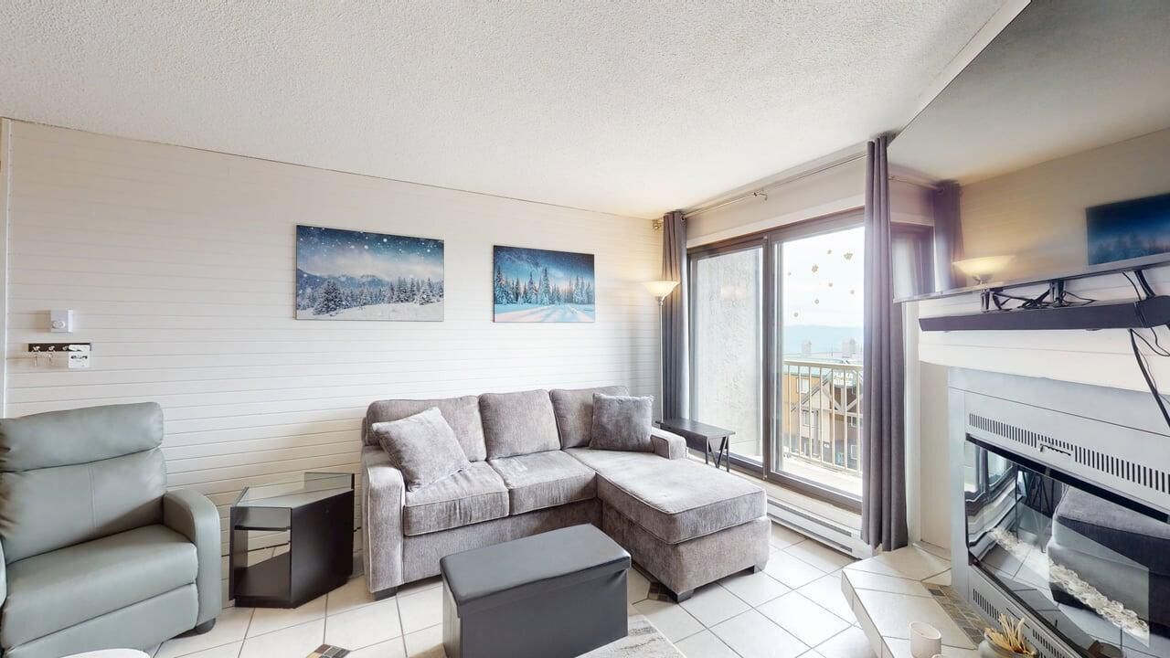 Ein modernes Wohnzimmer mit einem Ecksofa, einem kleinen Tisch und einem Kamin.