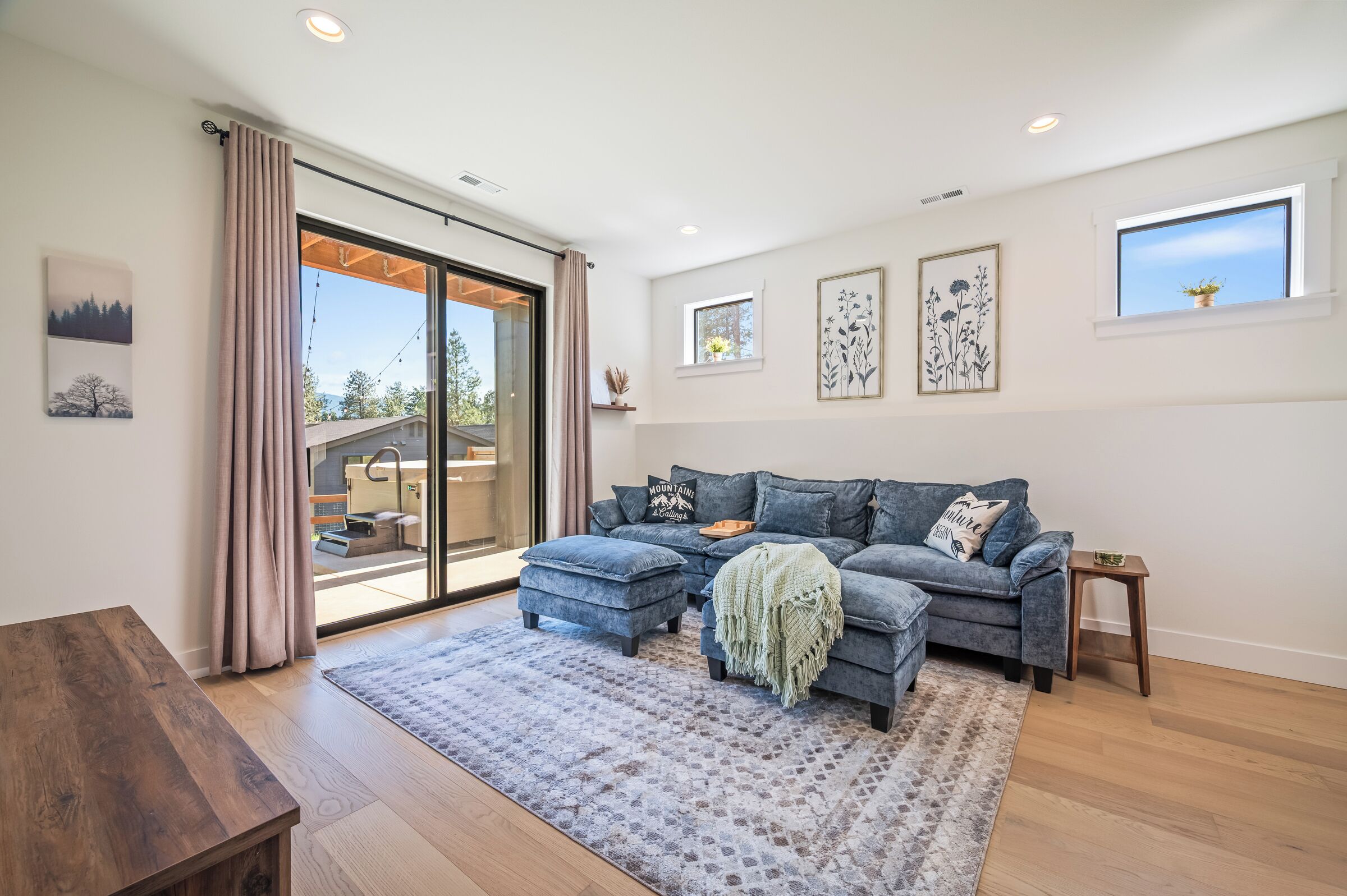 A modern living room with a sectional sofa, a wooden coffee table, and a large sliding glass door leading to an outdoor area.