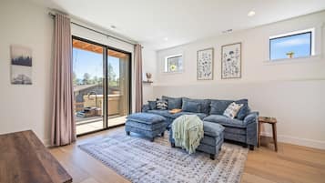 A modern living room with a sectional sofa, a wooden coffee table, and a large sliding glass door leading to an outdoor area.