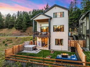 A two-story house with a balcony, outdoor seating, and a hot tub.
