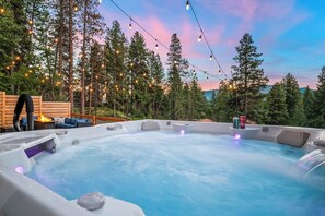 A hot tub surrounded by trees, with string lights and a wooden deck. - Welcome to Outfitter Retreat, a mountain getaway within walking distance of Historic Downtown Cle Elum. Enjoy hiking, biking, ATV trails, golf, and year-round adventure. Each space has been designed to provide you with an unforgettable experience. (Cle Elum)