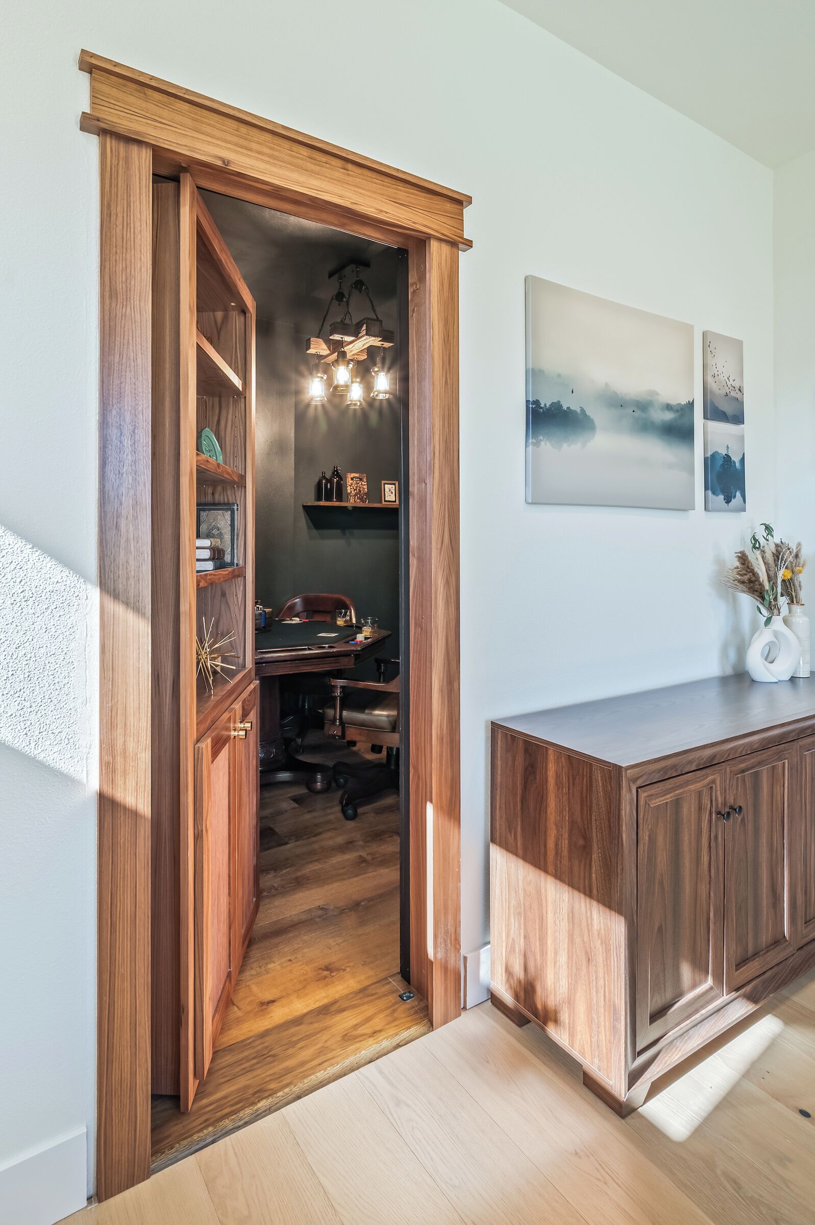 Un meuble en bois doté d’un bureau intégré, d’un luminaire suspendu et d’œuvres d’art accrochées au mur.