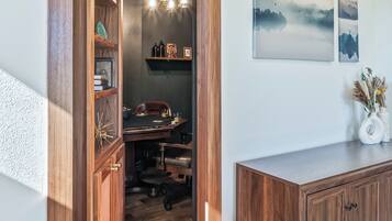 Un meuble en bois doté d’un bureau intégré, d’un luminaire suspendu et d’œuvres d’art accrochées au mur.