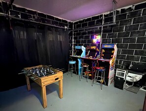 Ein Raum mit einem Kicker, Spielautomaten und einem Mülleimer.