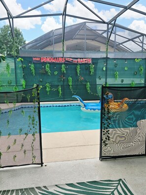 Ein Poolbereich mit grüner, mit Pflanzen bepflanzter Wand und einem Banner mit der Aufschrift 'WHEN DINOSAURS RULED THE EARTH'.