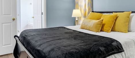 A bedroom with a bed, a door, a ceiling fan, and a wall with decorative elements.