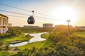 A golf course with a water feature, a cable car, and modern buildings in the background. - Grand Mayan Nuevo Vallarta Mstr Suite  Oct 26-Nov 2, 6 Free Breakfast, 2 Massage (Las Jarretaderas)
