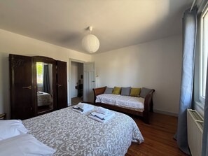 Ein Schlafzimmer mit einem großen Bett, einem Schlafsofa, einem Kleiderschrank und einer Pendelleuchte.