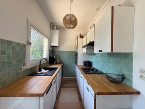 Eine Küche mit Fenster, Spüle, Herd und Schränken.