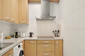 Una cucina moderna con mobili in legno, una cappa aspirante in acciaio inossidabile, una lavatrice integrata e un piano di lavoro con diversi elettrodomestici.