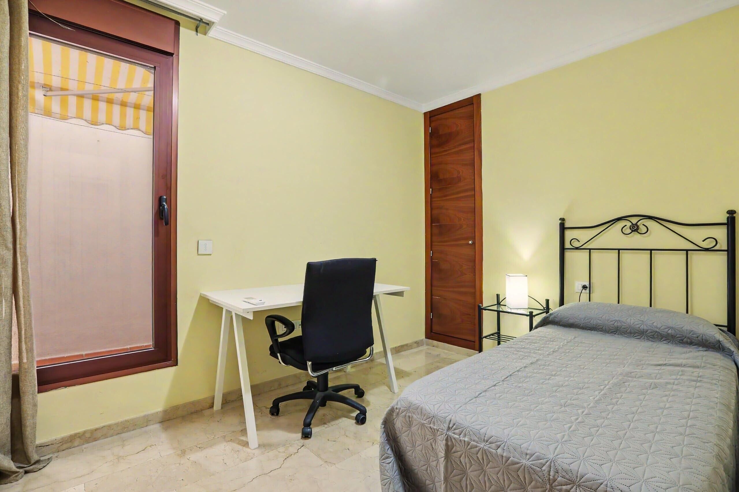 A bedroom with a bed, a desk, and a chair.