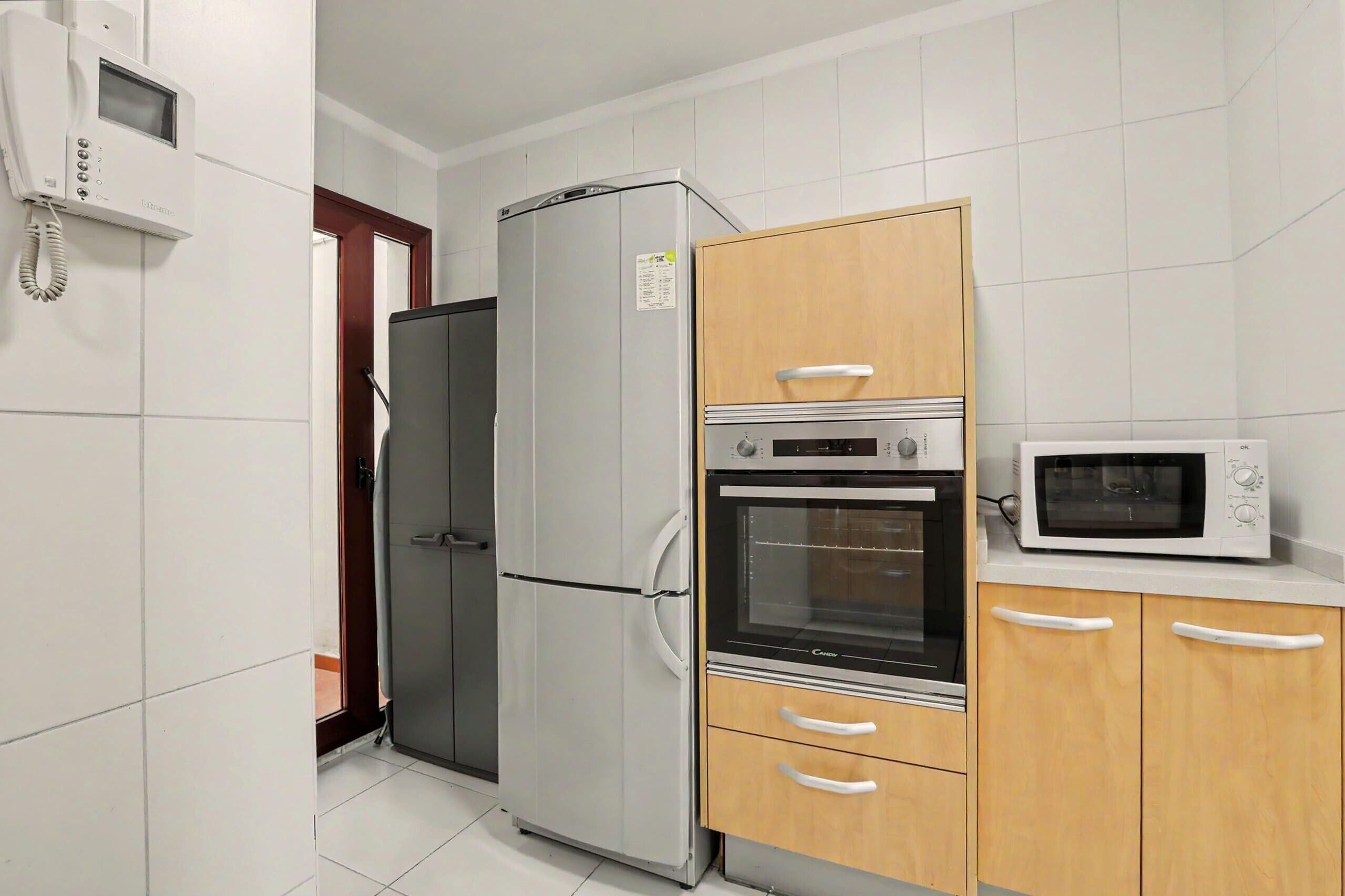 A kitchen with a refrigerator, oven, microwave, and wooden cabinets.