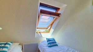 Una habitación con dos camas, una ventana y una rejilla en el techo.