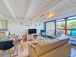 A modern living room with a TV, sofa, dining table, and chairs.