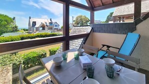 Un balcón con una mesa lista para comer, con vista a un barrio residencial con casas y cielo despejado.