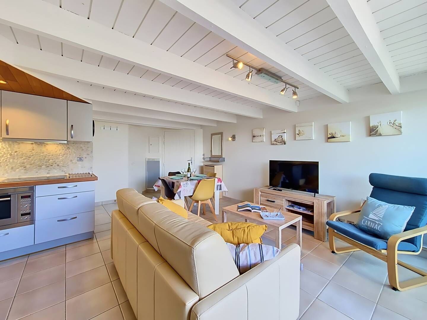 Un salon moderne comprenant un canapé, un téléviseur et un coin repas avec une table et des chaises.