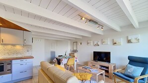 Una sala de estar moderna con un sofá, una televisión y un comedor con una mesa y sillas.