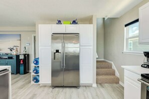 Eine moderne Küche mit einem Edelstahlkühlschrank, Wasserspendern und einer Kaffeemaschine auf der Arbeitsfläche.