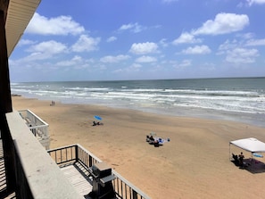 Ein Strand mit einer Holzterrasse, einem Grill und einem Zelt.