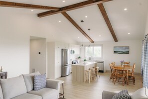 A modern kitchen with a central island, wooden beams, and pendant lighting. - Brand New Cottage in Stratford-Hot Tub, incredible water view! (Stratford)