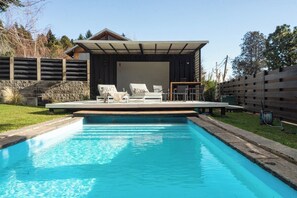 Une piscine avec des chaises longues et un espace patio couvert.