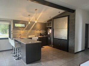 A modern kitchen with a large island, bar stools, and a view of the outdoors. - House with a pool and a gym (San Carlos de Bariloche)