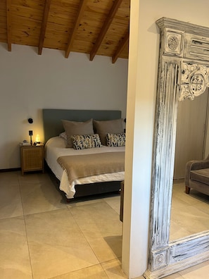 A bedroom with a bed, bedside table, lamp, and a large mirror. - House with a pool and a gym (San Carlos de Bariloche)
