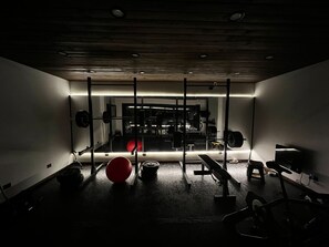 A dimly lit gym with weightlifting equipment, a red exercise ball, and benches. - House with a pool and a gym (San Carlos de Bariloche)