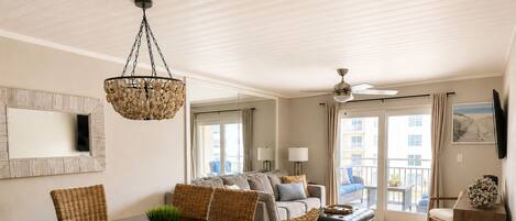 A modern living room with a dining area, a ceiling fan, and a large window with a view.