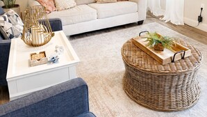 Ein Wohnzimmer mit einer Couch, einem Couchtisch, einer Stehlampe, einem Gemälde und einer Topfpflanze.