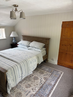 A bedroom with a wooden bed, a patterned rug, a lamp, and a ceiling light fixture.