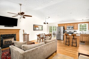 A modern kitchen with wooden cabinets, stainless steel appliances, and a dining area with a table and chairs. - Basye Bungalow | Spacious 4BR/3BA cabin with hot tub, fire pit, deck (Basye)