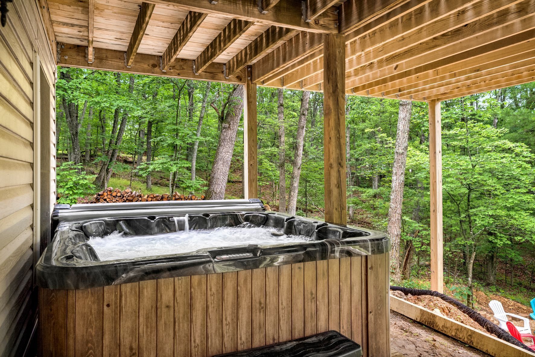 A hot tub in a wooden structure surrounded by trees.