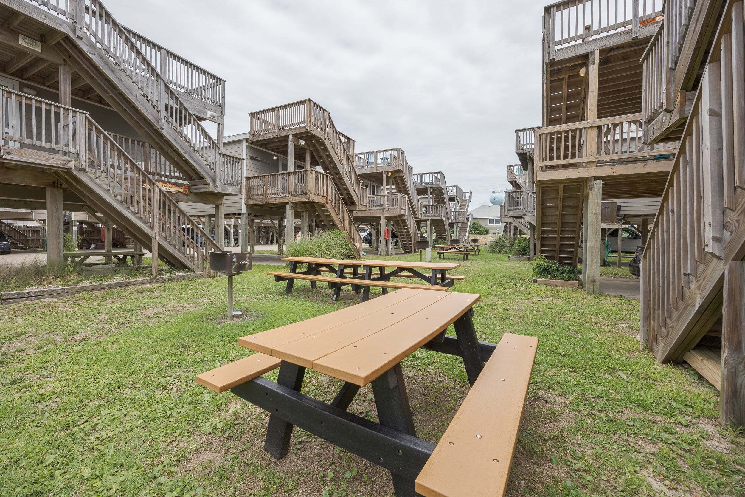 Un espace pique-nique équipé de tables en bois et une aire de jeux avec des structures et des escaliers en bois.