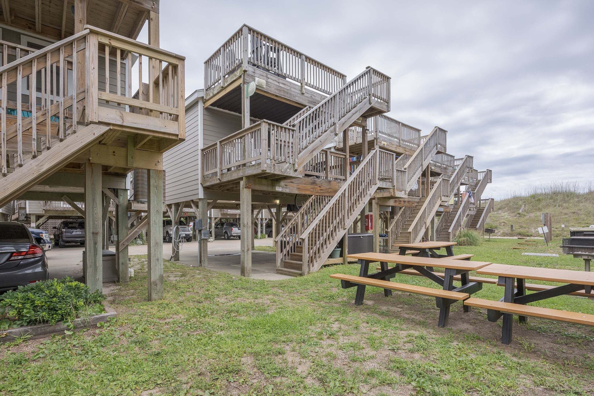A multi-level wooden structure with outdoor seating and a parking area.