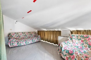 Una habitación con dos sofás tapizados con estampado floral, suelo de baldosas e iluminación empotrada en el techo.
