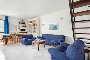 A living room with a blue sofa set, a wooden coffee table, and a dining area with a table and chairs.