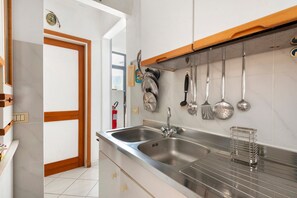 Una cocina con dos fregaderos de acero inoxidable, una encimera de madera y diversos utensilios de cocina colgados en la pared.