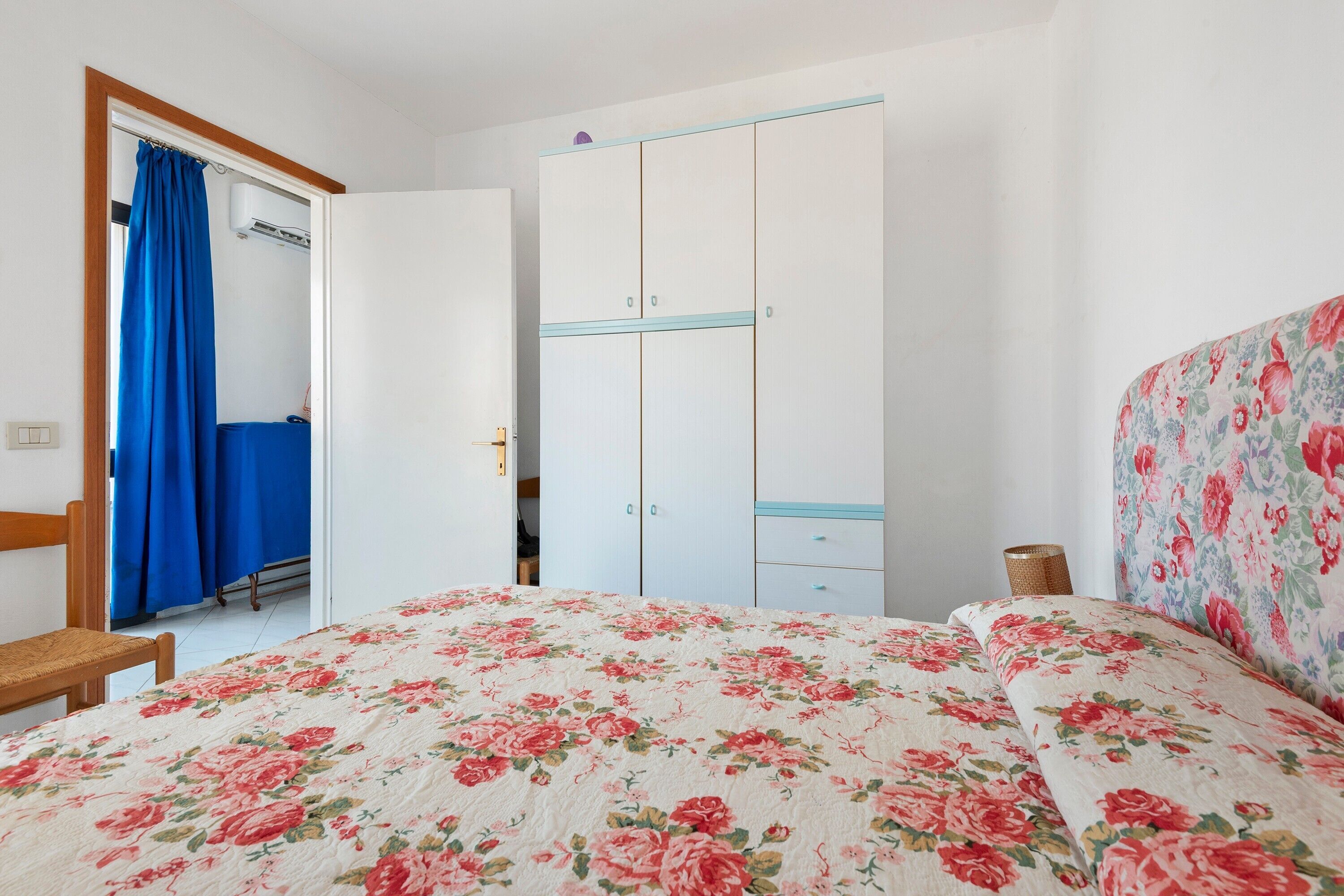 A bedroom with a bed, a wardrobe, a chair, and a curtain.