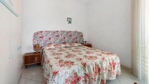 A bedroom with a floral bedspread, wooden nightstands, a small bedside table, and a framed picture on the wall.