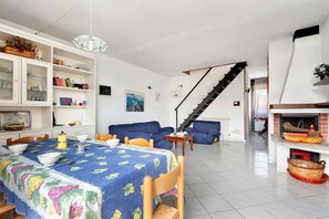 Ein Wohnzimmer mit Esstisch, Sofas, Kamin und einer Wendeltreppe.
