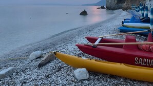 A beach with kayaks and a rocky shoreline.
