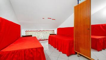 A room with red beds, a wooden wardrobe, and a tiled floor.
