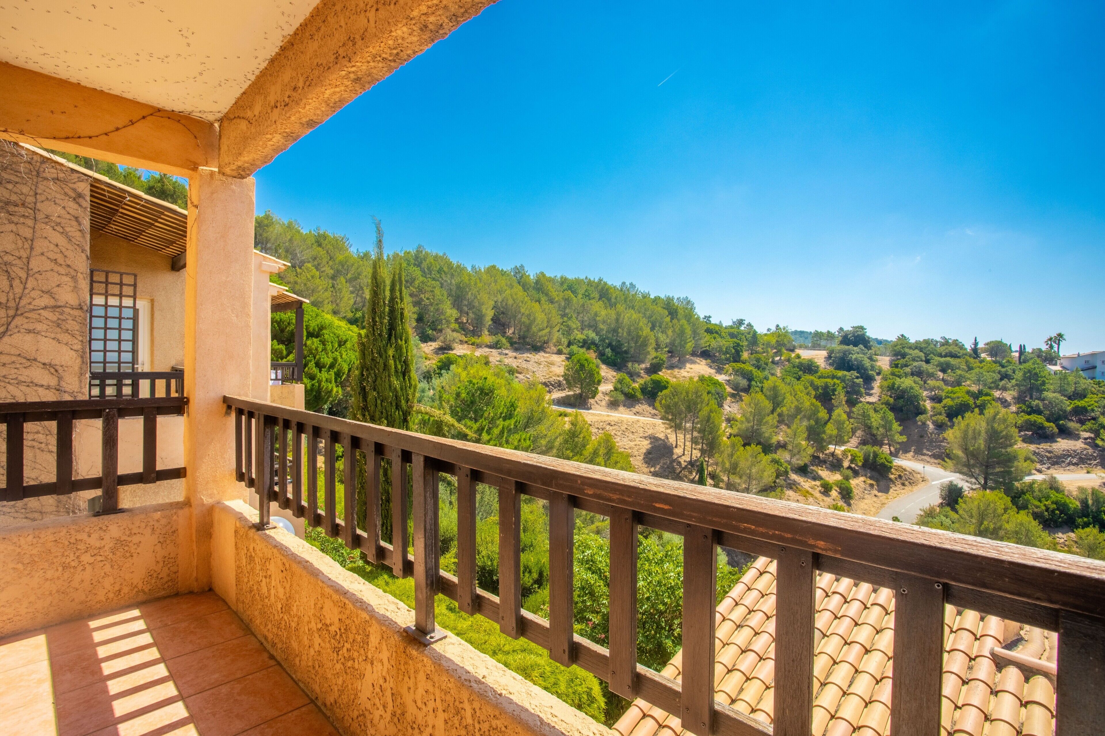 Un balcon donnant sur un paysage verdoyant et un ciel dégagé.