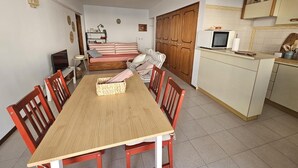 Ein kompakter Wohnbereich mit Esstisch, Stühlen, einer Couch, einer Küchenzeile und einem Kleiderschrank.