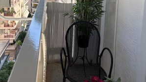 Ein Balkon mit einem Stuhl, einem Blumentopf und einem grünen Sonnenschirm.