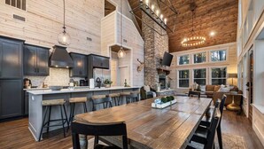 Una cocina amplia con una isla grande, muebles oscuros y una chimenea de piedra.